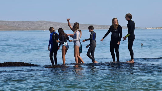 Kids learning to surf in Cape Town wearing Octohoodie swim ponchos on the beach