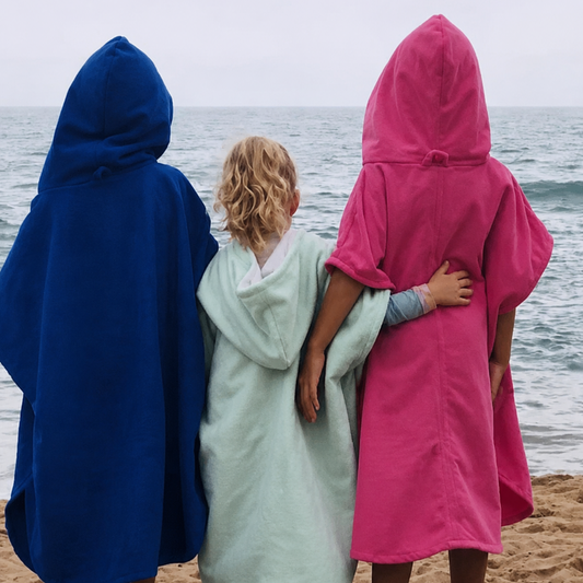 Three children standing on a sandy beach with their backs to the camera, each wearing a hooded Octohoodie short-sleeve