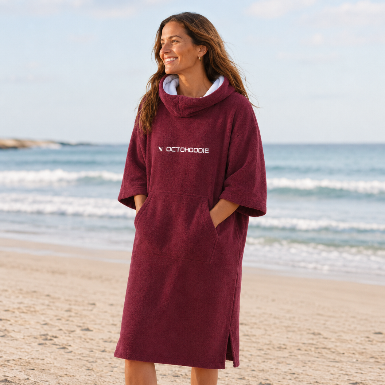 A woman wearing a maroon long-sleeve Octohoodie on the beach