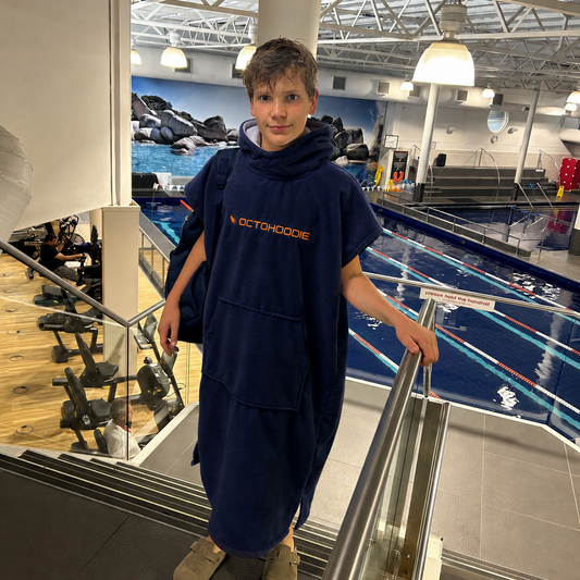Teenage boy at the gym after a swim wearing an adults and teens short-sleeve Octohoodie in Atlantic Ember. 