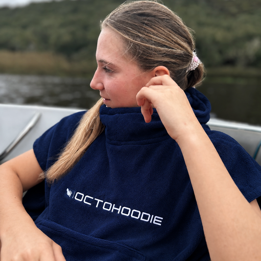 A woman sitting on a boat wearing a navy blue Octohoodie 