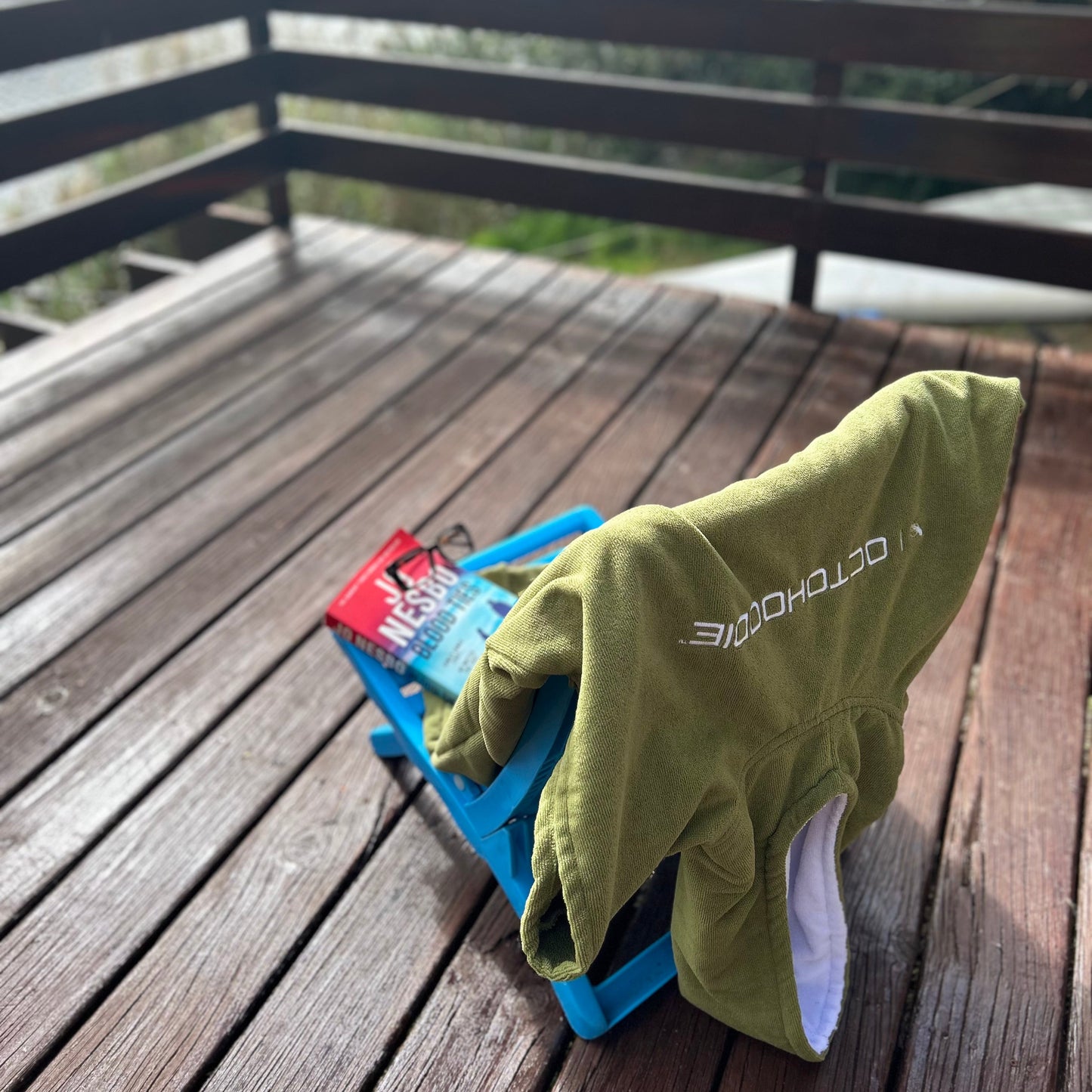 Octohoodie swimming poncho on a wooden deck overlooking a lake.