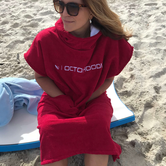 Woman at beaech sitting on a boogie board wearing a Sunrise Red Octohoodie